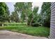 Backyard with green grass and mature trees with a concrete patio at 9036 W Wisconsin Ave, Lakewood, CO 80232
