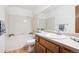 Clean bathroom featuring a tub, shower, tile wall, and vanity with sink and wood cabinets at 9036 W Wisconsin Ave, Lakewood, CO 80232