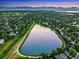 Aerial view of neighborhood with lake, walking trail, and mountain views beyond the verdant green trees at 8940 W 80Th Dr, Arvada, CO 80005