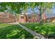Charming backyard featuring a brick house, lush green lawn, and mature tree providing shade at 1434 Clermont St, Denver, CO 80220