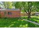 Lush backyard with a brick garage nestled beneath mature trees, surrounded by a well-maintained lawn at 1434 Clermont St, Denver, CO 80220