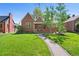 Charming brick home with a well-manicured lawn, inviting pathway, and mature trees creating curb appeal at 1434 Clermont St, Denver, CO 80220