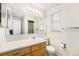 Bathroom featuring vanity sink, toilet, large mirror, and a shower with glass door at 5190 W Mexico Ave, Denver, CO 80219