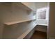 Well-lit pantry featuring floor-to-ceiling white shelving, wood flooring, and a window for natural light at 2831 N Perry St, Denver, CO 80212