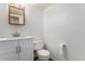 Bathroom with a white vanity, modern sink fixture, wood-framed mirror, and toilet with white walls at 8236 E Phillips Pl, Centennial, CO 80112