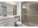 Bathroom featuring an enclosed shower, large mirror, white vanity, and toilet at 8236 E Phillips Pl, Centennial, CO 80112