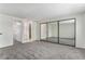 Large bedroom featuring gray carpet, an en suite bathroom, and expansive mirrored sliding closet doors at 8236 E Phillips Pl, Centennial, CO 80112