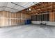 Unfinished garage with visible framing and blue trash bins with concrete floors at 8236 E Phillips Pl, Centennial, CO 80112