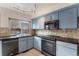 Kitchen with black appliances, countertops, blue cabinets, and stylish backsplash at 8236 E Phillips Pl, Centennial, CO 80112