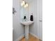 Powder room featuring a pedestal sink, updated lighting, and hardwood floors at 719 Robert St, Longmont, CO 80503