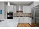 Well-designed kitchen features stainless steel appliances, white cabinets, and a stunning backsplash at 719 Robert St, Longmont, CO 80503