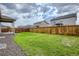 Backyard featuring a well-maintained lawn and wooden fence with neighboring houses in the background at 13667 Valentia St, Thornton, CO 80602