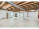 Unfinished basement features concrete floors and walls with plastic sheeting and exposed wood ceiling and support beams at 13667 Valentia St, Thornton, CO 80602