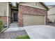 Exterior of home with a two-car garage, concrete driveway, and brick and siding accents on the facade at 13667 Valentia St, Thornton, CO 80602