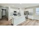 Bright kitchen featuring stainless steel appliances, white cabinetry, a large island with seating, and wood-look floors at 13667 Valentia St, Thornton, CO 80602