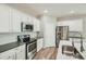 Bright kitchen featuring stainless steel appliances, white cabinets and backsplash, and quartz countertops at 13667 Valentia St, Thornton, CO 80602