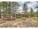 Secluded backyard view featuring a patio area, mature trees, and a charming red footbridge at 19475 Stag Ln, Monument, CO 80132