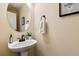 Small bathroom with pedestal sink, round mirror, and decorative art at 10654 Ashfield St, Highlands Ranch, CO 80126