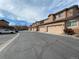 View of several townhome garages, with tan exteriors and matching garage doors, set against a blue sky and tree line at 4519 S Atchison Way, Aurora, CO 80015