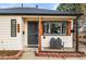 Close up of cozy front porch with chairs, black door, and brick border at 2020 Gray St, Edgewater, CO 80214