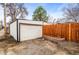 A detached garage, next to a wood fence, sits off an alley in this home's back yard at 2020 Gray St, Edgewater, CO 80214