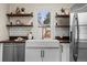 White farmhouse sink with modern fixtures, open shelving, and stainless steel dishwasher at 2020 Gray St, Edgewater, CO 80214