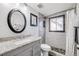 Neutral bathroom featuring a granite countertop, brushed nickel faucet, oval mirror, and tiled shower with stone flooring at 13654 Omega Cir, Lone Tree, CO 80124