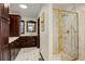 Luxurious bathroom with marble countertops, dark wood cabinets, and glass enclosed shower with gold trim at 9526 E Lake Ave, Greenwood Village, CO 80111