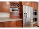 Kitchen area with stainless steel fridge, built in microwave, wooden cabinets and granite countertop at 9526 E Lake Ave, Greenwood Village, CO 80111