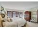 Light-filled bedroom featuring large armoire, three pane windows with Juliet balcony, and soft white carpet at 9526 E Lake Ave, Greenwood Village, CO 80111