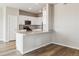 Modern kitchen featuring white cabinets, stainless steel appliances, a breakfast bar, and wood-look floors at 48245 Shetland Dr, Bennett, CO 80102