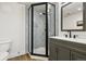 Bathroom featuring a modern glass enclosed shower with decorative tile and dark vanity at 6388 Donner Cir, Parker, CO 80134