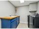 Bright laundry room with blue cabinets, butcher block countertop, and modern appliances at 6388 Donner Cir, Parker, CO 80134