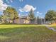 Large backyard area with lawn, trees, and a shed-like building and fenced-in area to the right at 8700 Flintwood Rd, Parker, CO 80138