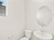Clean half-bath featuring a pedestal sink, toilet, oval mirror and natural light through the blinds at 6068 Hourglass Dr, Brighton, CO 80601