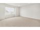 Spacious bedroom with neutral carpet, white walls, and a large window providing plenty of natural light at 6068 Hourglass Dr, Brighton, CO 80601