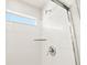 Close-up of a modern shower with white tile, chrome fixtures, a glass door and a built in storage shelf at 6068 Hourglass Dr, Brighton, CO 80601