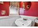 Red bathroom featuring a white pedestal sink, decorative mirror, and a vintage-inspired aesthetic at 912 S Washington St, Denver, CO 80209