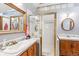 Bathroom featuring a tiled shower with a glass door and double sinks with wooden cabinets at 912 S Washington St, Denver, CO 80209