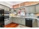 Stylish kitchen featuring stainless steel appliances, granite countertops, grey cabinets, and a unique exposed brick wall design at 912 S Washington St, Denver, CO 80209