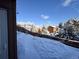 View of the snow covered backyard showing homes and trees beyond the fence at 30819 Hilltop Dr, Evergreen, CO 80439