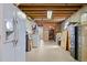 Unfinished basement area with exposed ceiling beams, refrigerator, and storage shelving at 17445 County Road 6, Brighton, CO 80603