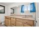 Bathroom featuring a dual sink vanity, large mirror, and a window providing natural light at 17445 County Road 6, Brighton, CO 80603