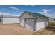 View of white outbuilding with green roof and white door, with a larger metal building adjacent at 17445 County Road 6, Brighton, CO 80603