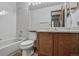 Bathroom featuring wood cabinets, a toilet, a tub with shower, and a large mirror at 9669 Jellison Way, Broomfield, CO 80021