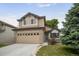 Charming two-story home featuring tan siding, brick accents, landscaped yard, and an attached two car garage at 9669 Jellison Way, Broomfield, CO 80021