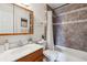 Cozy bathroom with neutral tile, decorative accents and shower-tub combo behind a floral trimmed curtain at 8625 W Dartmouth Pl, Lakewood, CO 80227