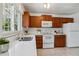 Well-lit kitchen boasting quartz counters, white appliances, and beautiful wood cabinetry at 8625 W Dartmouth Pl, Lakewood, CO 80227