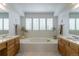 Bright and open bathroom featuring dual vanities, a large tub, and shuttered windows at 14261 W Evans Cir, Lakewood, CO 80228