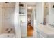 Bright bathroom featuring tiled shower-tub, a decorative tiled backsplash, and open shelving for storage at 2281 Florence St, Aurora, CO 80010